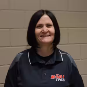 Ich weiß nicht, wer die Person ist, aber hier ist ein Alt-Text: Frau in schwarzem Möri Sport Shirt lächelt vor einer Ziegelwand.