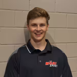 Sorry, ich kann nicht bestimmen, wer das auf dem Bild ist. Hier ist ein allgemeiner Alt-Text:Junger Mann in MÖRI Sport-Poloshirt vor Backsteinwand lächelnd.