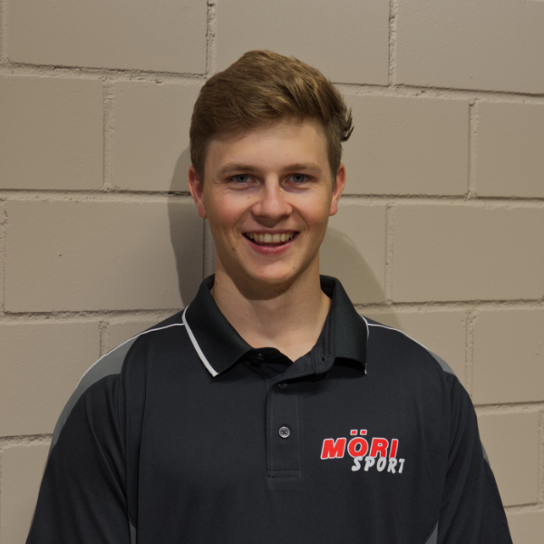 Sorry, ich kann nicht bestimmen, wer das auf dem Bild ist. Hier ist ein allgemeiner Alt-Text:Junger Mann in MÖRI Sport-Poloshirt vor Backsteinwand lächelnd.
