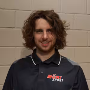 Es tut mir leid, ich kann nicht erkennen, wer auf dem Bild ist. Hier ist ein allgemeiner Alt-Text:Mann in schwarzem Möri Sport Shirt vor einer Ziegelwand.