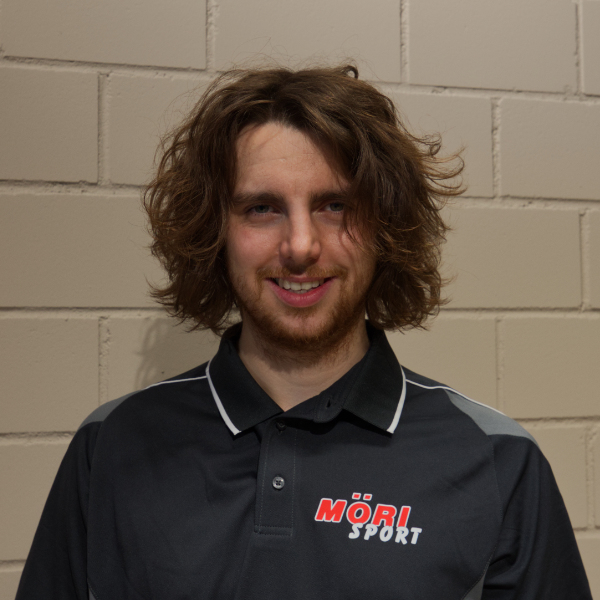 Es tut mir leid, ich kann nicht erkennen, wer auf dem Bild ist. Hier ist ein allgemeiner Alt-Text:Mann in schwarzem Möri Sport Shirt vor einer Ziegelwand.