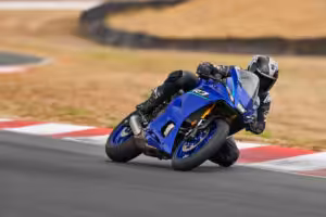 Motorradfahrer auf einer Rennstrecke in Schräglage, blaue Sportmaschine, schnelles Fahren, präzise Kurventechnik.