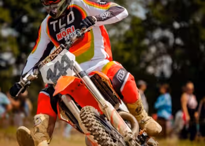 Motocross-Fahrer in Action auf einer staubigen Strecke während eines Rennens, in voller Ausrüstung und Helm.