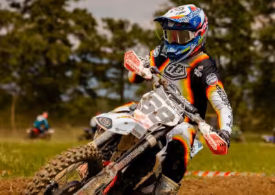 Motorradfahrer drifts in Kurve auf schlammiger Rennstrecke, dynamische Action und Bewegung im Rennen eingefangen.